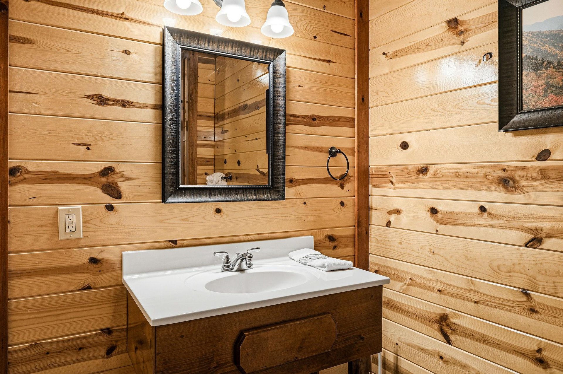 Refresh in your rustic bathroom where knotty pine walls and warm lighting create a cozy cabin atmosphere.