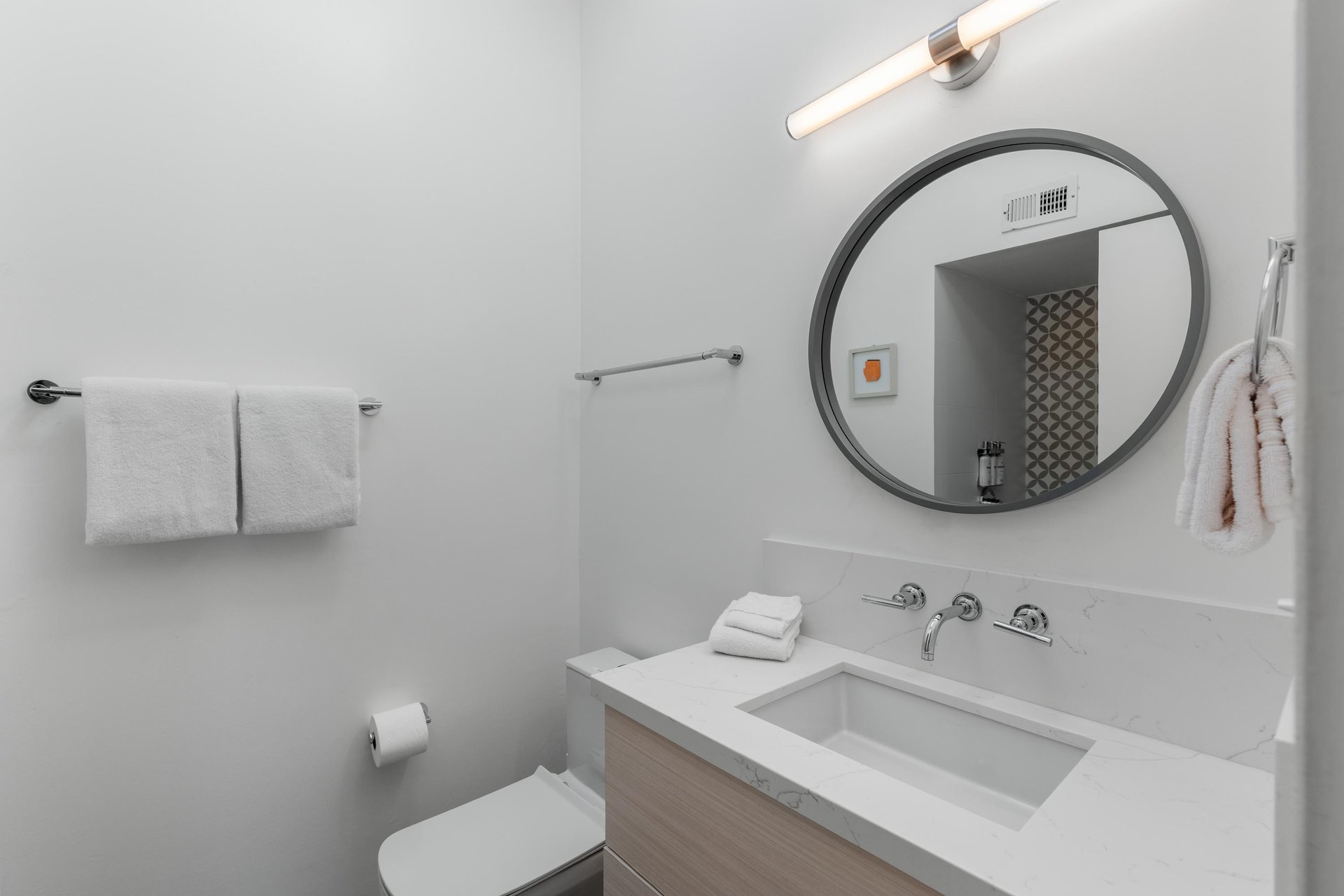 Fresh white bathroom with modern finishes awaits your morning routine, complete with fluffy towels and stylish round mirror.