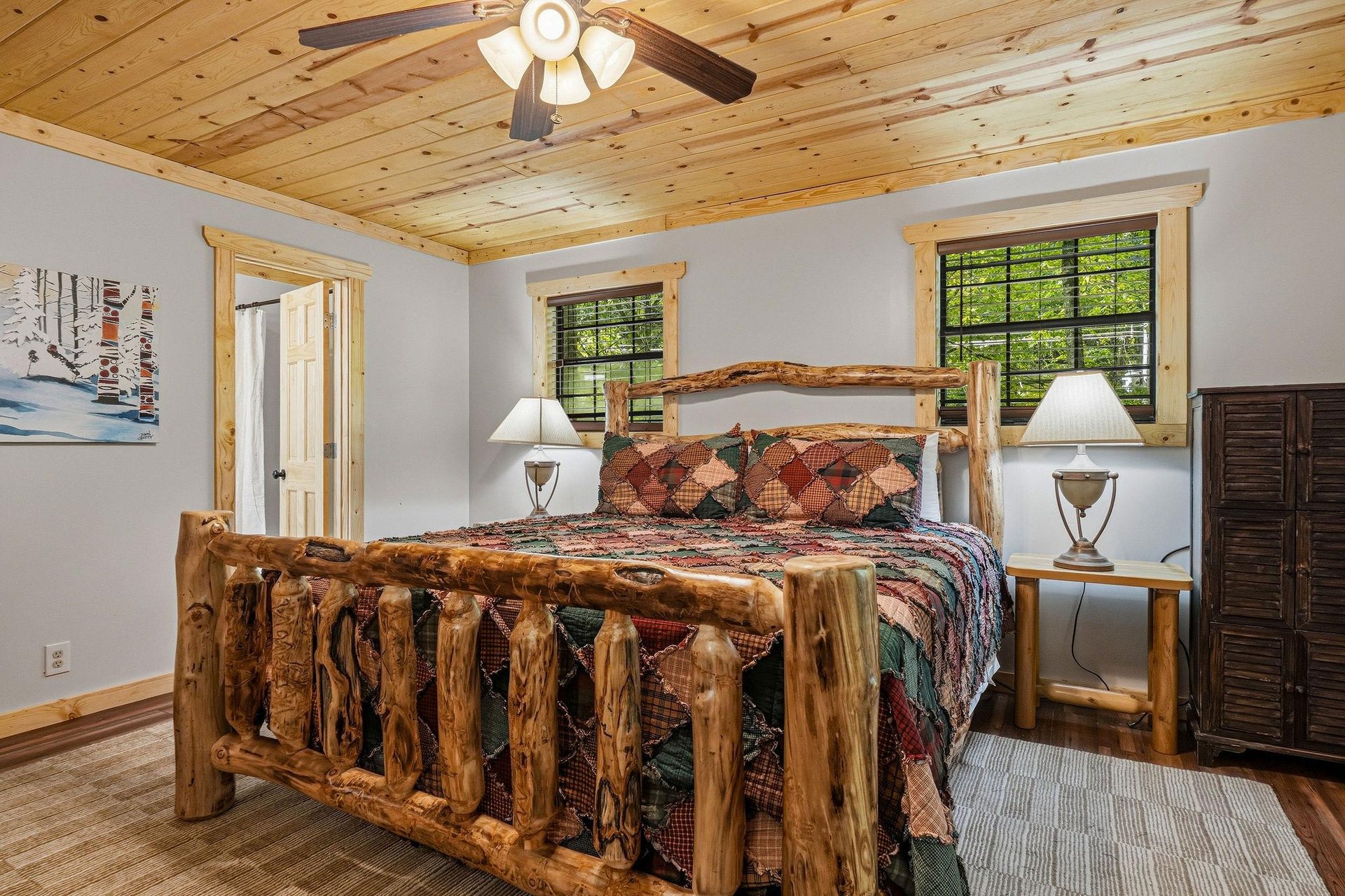 Retreat to your cozy bedroom featuring a stunning handcrafted log bed beneath warm pine ceilings. Natural light streams through large windows while the rustic charm and thoughtful details create your 