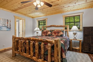 Retreat to your cozy bedroom featuring a stunning handcrafted log bed beneath warm pine ceilings. Natural light streams through large windows while the rustic charm and thoughtful details create your 