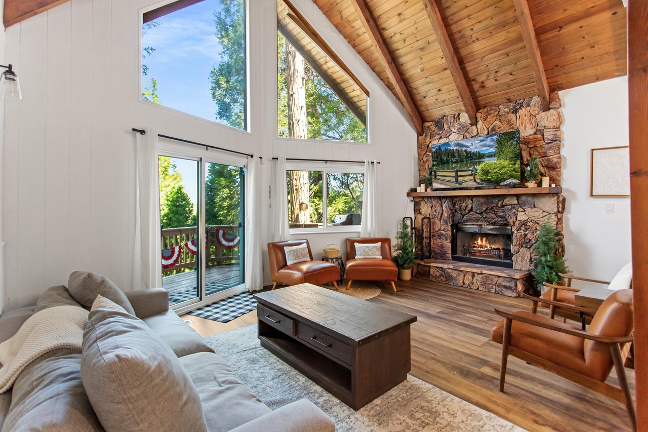 Soaring vaulted ceilings, fireplace, flatscreen TV, and spacious deck with treetop and lake views.