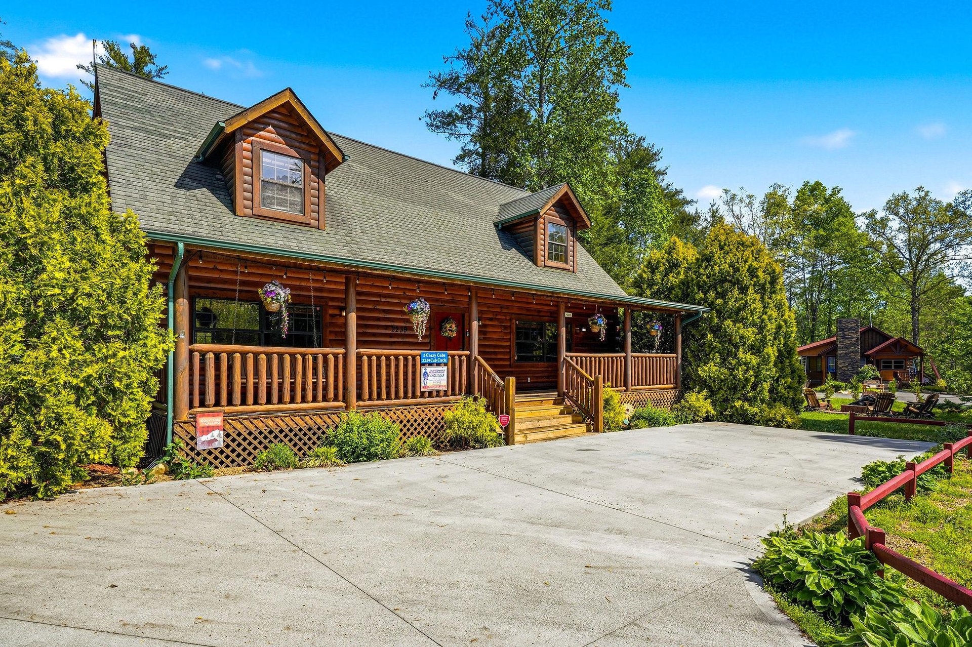 Charming log cabin retreat with wraparound porch and convenient parking, nestled among lush trees for a perfect mountain getaway.