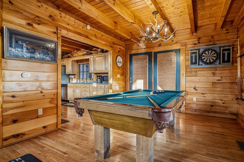 Challenge friends to a game of pool or test your aim at the dartboard in this welcoming game room with soaring woodbeamed ceilings and a rustic antler chandelier overhead.