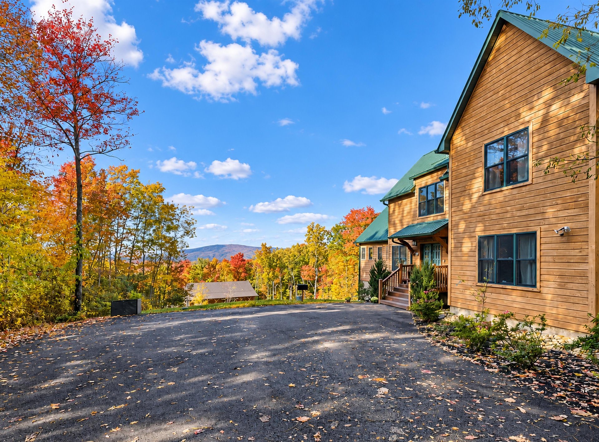 A welcoming mountain retreat featuring natural wood siding and vibrant fall foliage, with ample parking and stunning views of the surrounding landscape.