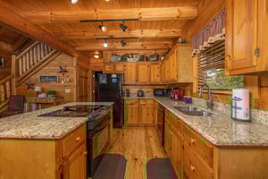 Galley kitchen with black appliances and granite counters at Livin Simple, a 2 bedroom cabin rental located in Pigeon Forge