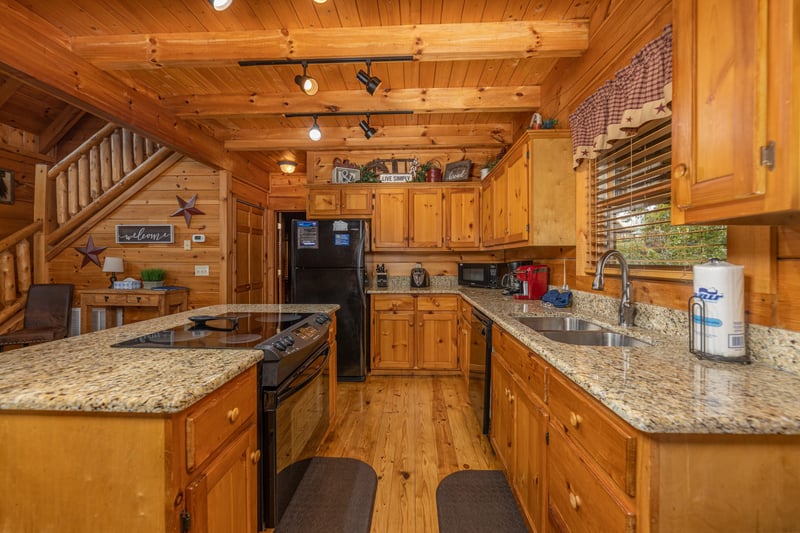 Galley kitchen with black appliances and granite counters at Livin Simple, a 2 bedroom cabin rental located in Pigeon Forge