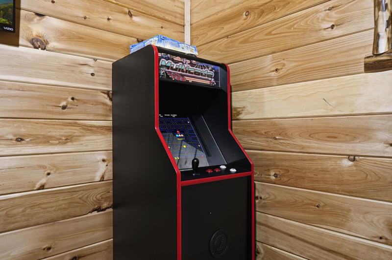 Challenge your friends to classic arcade games in this cozy game room with authentic retro charm and warm wood surroundings.