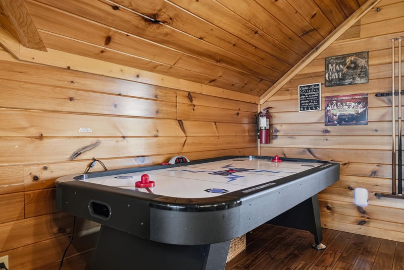 Challenge your friends to a game in this cozy cabin game room with air hockey, warm wood walls, and fun décor—perfect for unwinding after exploring the area.