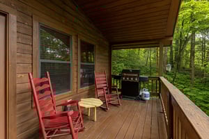 Rocking chairs and a grill on a covered porch