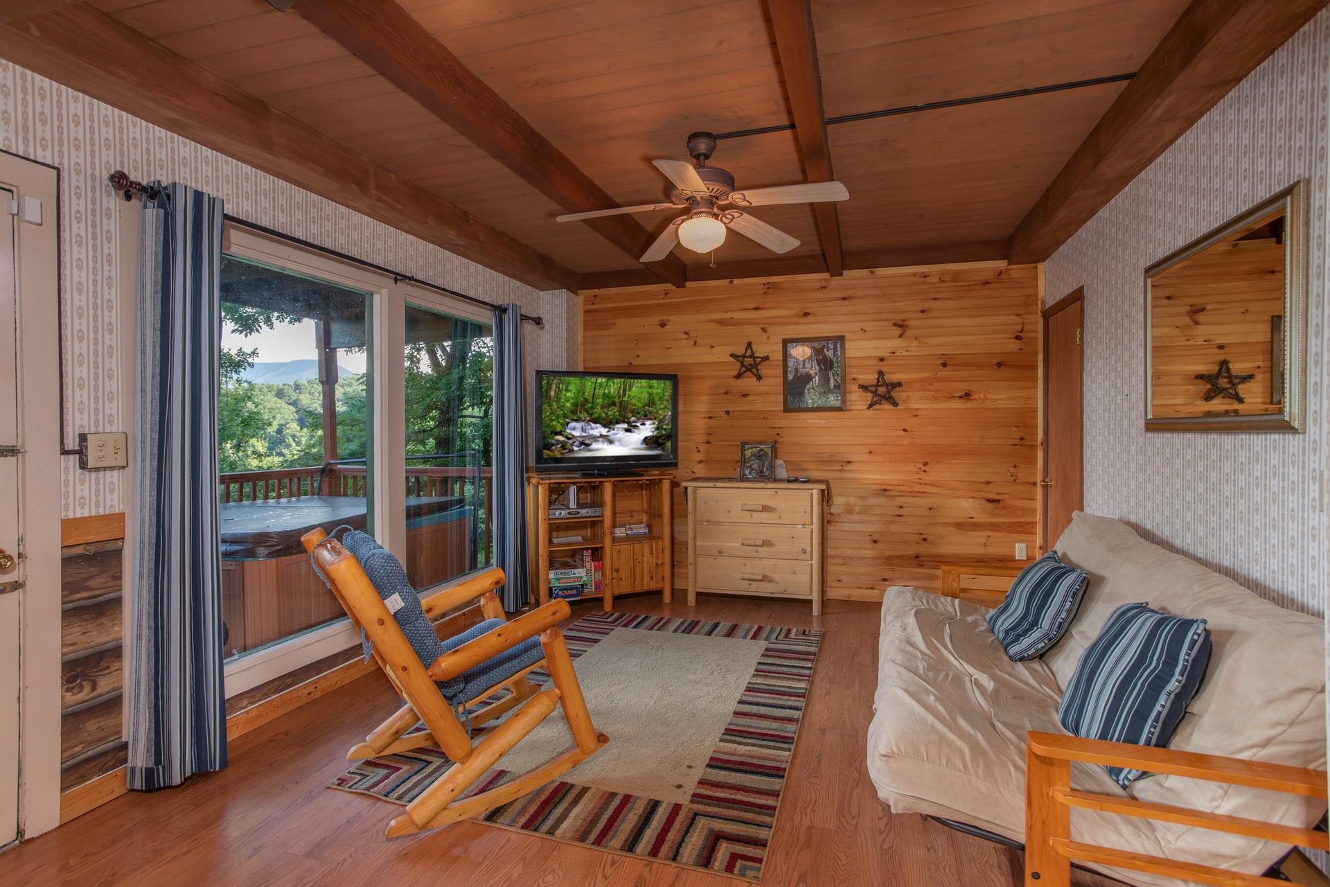Game room with a futon, wood rocking chair, and TV at Bushwood Lodge, a 3bedroom cabin rental located in Gatlinburg