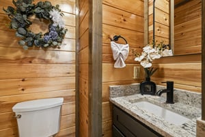 Youll love this charming bathrooms warm wood walls and granite vanity, perfectly appointed with elegant towel art and fresh orchids.