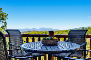 Sip your morning coffee at this inviting outdoor table, where sweeping mountain vistas and lush greenery create a peaceful backdrop for relaxation.