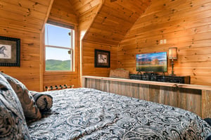 Wake up to mountain views framed by the warmth of natural wood in your cozy bedroom retreat. The vaulted ceiling and rustic charm create the perfect setting for restful mornings.