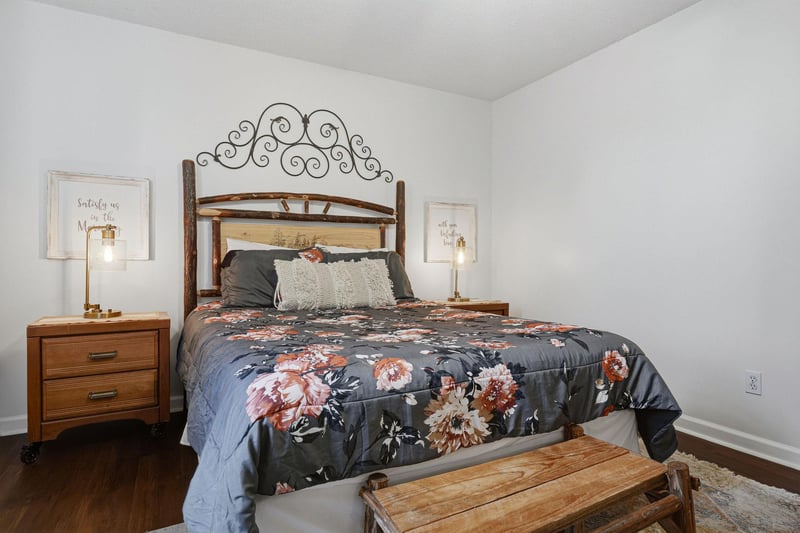 Your peaceful bedroom awaits, featuring a plush queen bed dressed in elegant floral linens, warm wood accents, and soft bedside lighting to help you unwind after exploring.