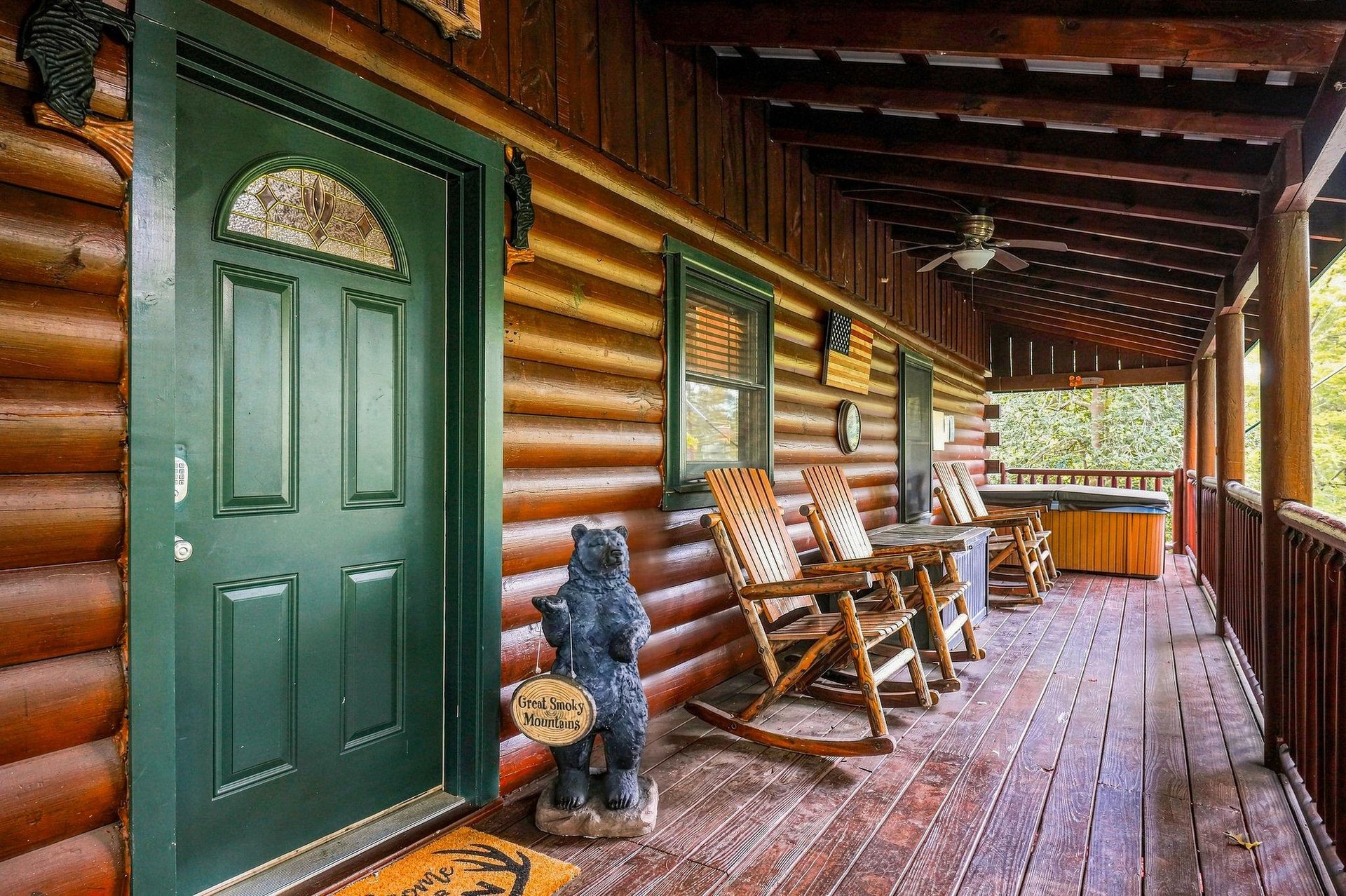 A welcoming covered porch invites you to settle into rustic rocking chairs, soak in the wooded surroundings, and unwind in your own private hot tub under the mountain breeze.
