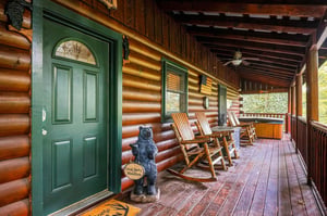 A welcoming covered porch invites you to settle into rustic rocking chairs, soak in the wooded surroundings, and unwind in your own private hot tub under the mountain breeze.