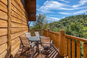 Dining space for four on an open deck at Great View Lodge, a 5bedroom cabin rental located in Pigeon Forge