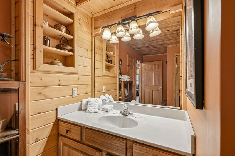 Your rustic cabin bathroom combines warm wood paneling with modern conveniences, creating a cozy retreat with thoughtful storage.