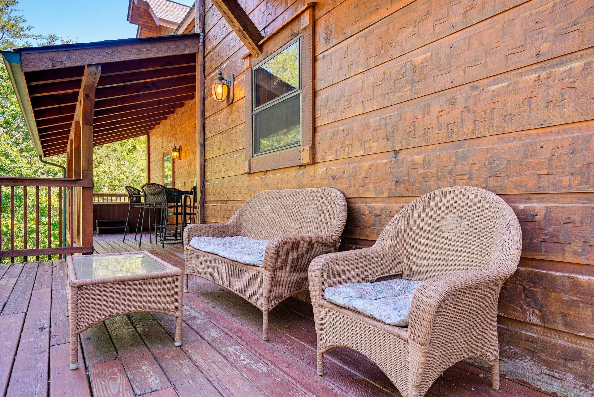 Your private deck invites relaxation with wicker seating and soft cushions, perfect for morning coffee or evening unwind surrounded by trees.