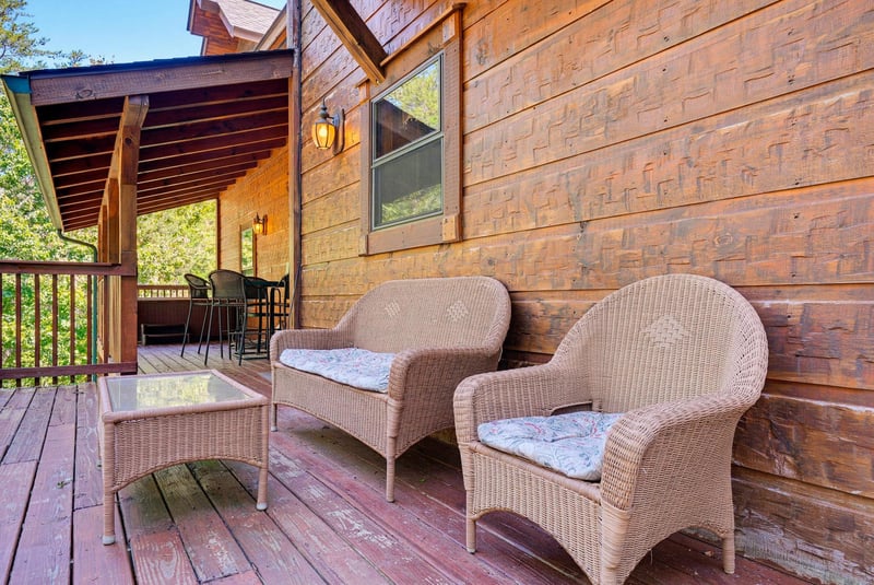 Your private deck invites relaxation with wicker seating and soft cushions, perfect for morning coffee or evening unwind surrounded by trees.