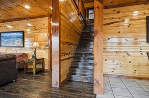Warm wooden walls embrace you as rustic stairs lead to your cozy retreat above, complete with comfortable seating.