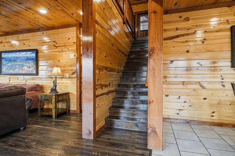 Warm wooden walls embrace you as rustic stairs lead to your cozy retreat above, complete with comfortable seating.