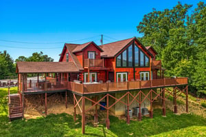 This spacious log cabin features multiple decks with scenic views, floortoceiling windows, and rustic charm nestled among lush trees—perfect for a peaceful mountain retreat.