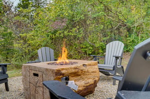 Gather around the rustic fire pit and let the warmth draw you in. Adirondack chairs await, surrounded by lush greenery, for peaceful evenings under the open sky.