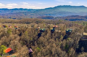 Breathtaking aerial view of mountain cabins nestled among rolling Appalachian peaks and forested valleys.