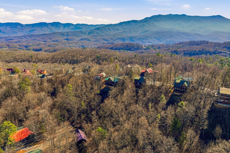 Breathtaking aerial view of mountain cabins nestled among rolling Appalachian peaks and forested valleys.