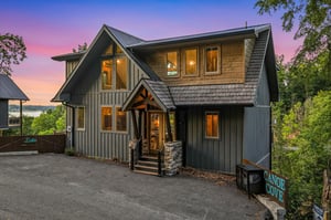 Charming lakeside retreat with modern rustic architecture, nestled among lush greenery and captured during a stunning twilight moment.
