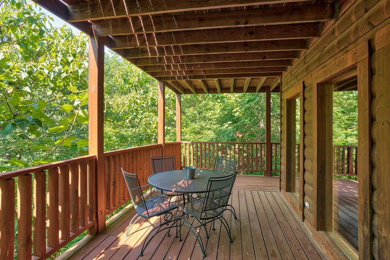 outdoor dining with space for four on a covered deck at angels majestic view a 3 bedroom cabin rental located in pigeon forge