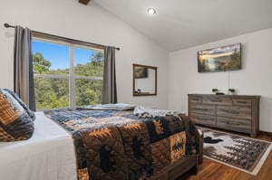 Wake up to peaceful views of lush treetops from your bright bedroom, where rustic charm meets modern comfort and natural light fills the space.