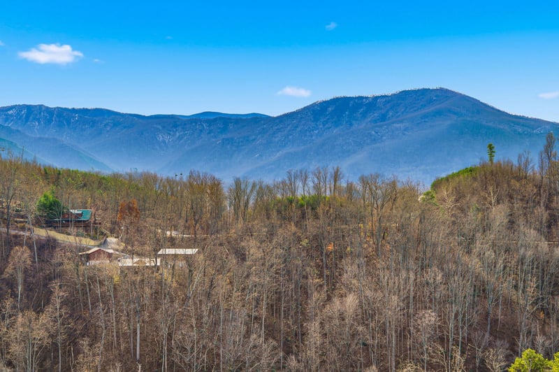 Spectacular mountain panorama stretches across the horizon, with rolling peaks and forested valley creating a stunning natural backdrop.
