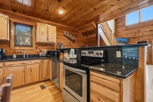 Step into your fullyequipped mountain retreat kitchen, where gleaming granite counters and modern appliances await your culinary adventures beneath warm woodpaneled ceilings and natural light.