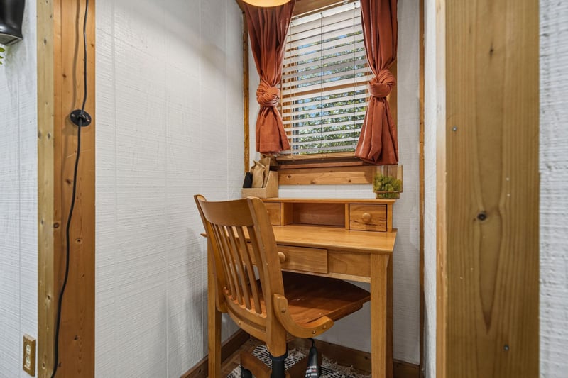 Your own quiet workspace awaits with warm wood furnishings and natural light filtering through charming curtains.