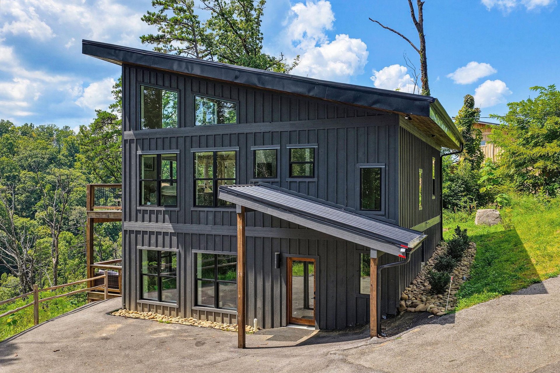 Modern mountain retreat with sleek architecture and forest surroundings, nestled on a hillside under blue skies.