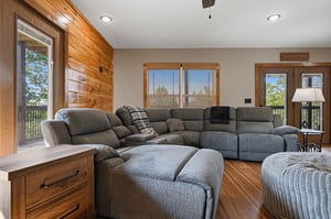 Stretch out on the spacious sectional and let natural light pour in through large windows that frame peaceful outdoor views. Warm wood accents create a cozy vibe perfect for unwinding.
