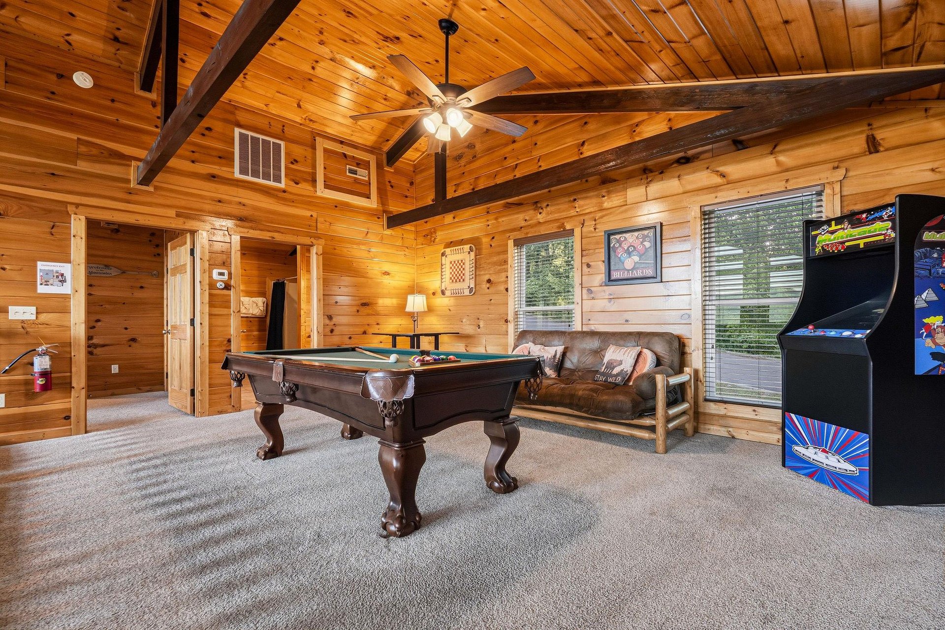 Your private game room awaits with rich wood beams, a fullsize pool table, classic arcade games, and a cozy leather sofa—perfect for friendly competition and unforgettable evenings.