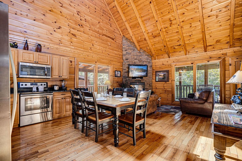 Step into your cozy mountain retreat with vaulted pine ceilings, a stone fireplace, and an open floor plan perfect for gathering. Sunlight pours through the windows as you settle in for meals at the d
