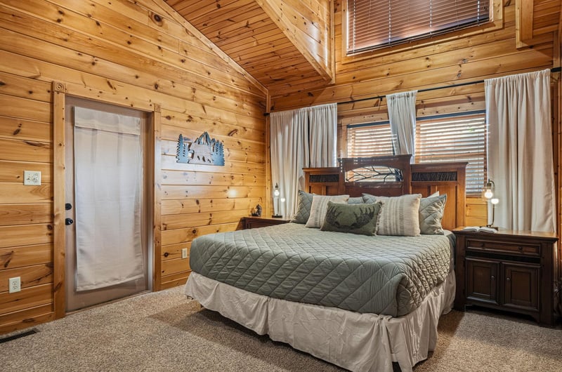 Unwind in your cozy cabin bedroom where warm wood walls embrace you and soft green bedding invites peaceful mountain dreams.