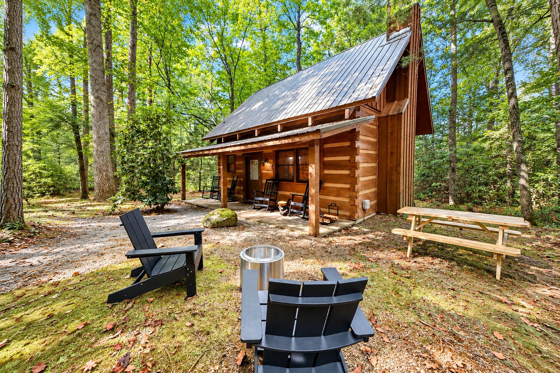 A charming log cabin nestled in a lush forest offers peaceful woodland surroundings. Relax by the fire pit or unwind on the covered porch with rocking chairs just steps away.