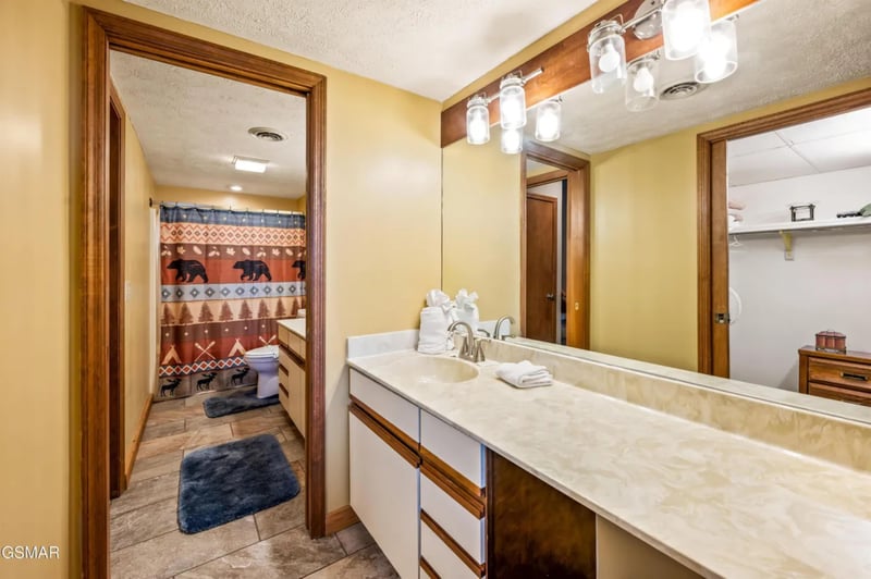 Step into your spacious bathroom featuring warm wood accents, elegant marble counters, and thoughtful amenities including fresh towels.