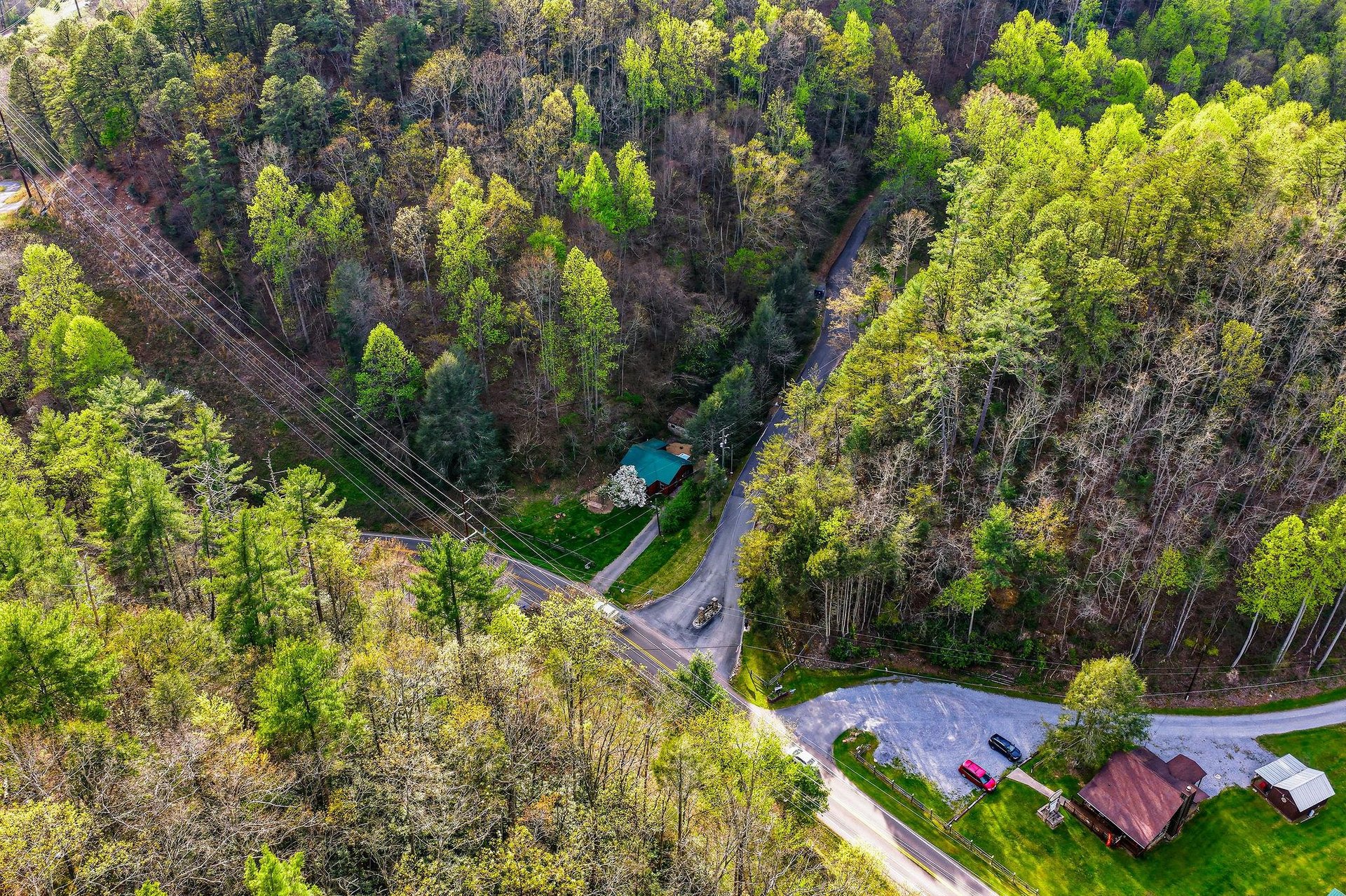Aerial view showcasing the property nestled in lush forest surroundings with convenient road access and peaceful natural setting.