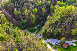 Aerial view showcasing the property nestled in lush forest surroundings with convenient road access and peaceful natural setting.