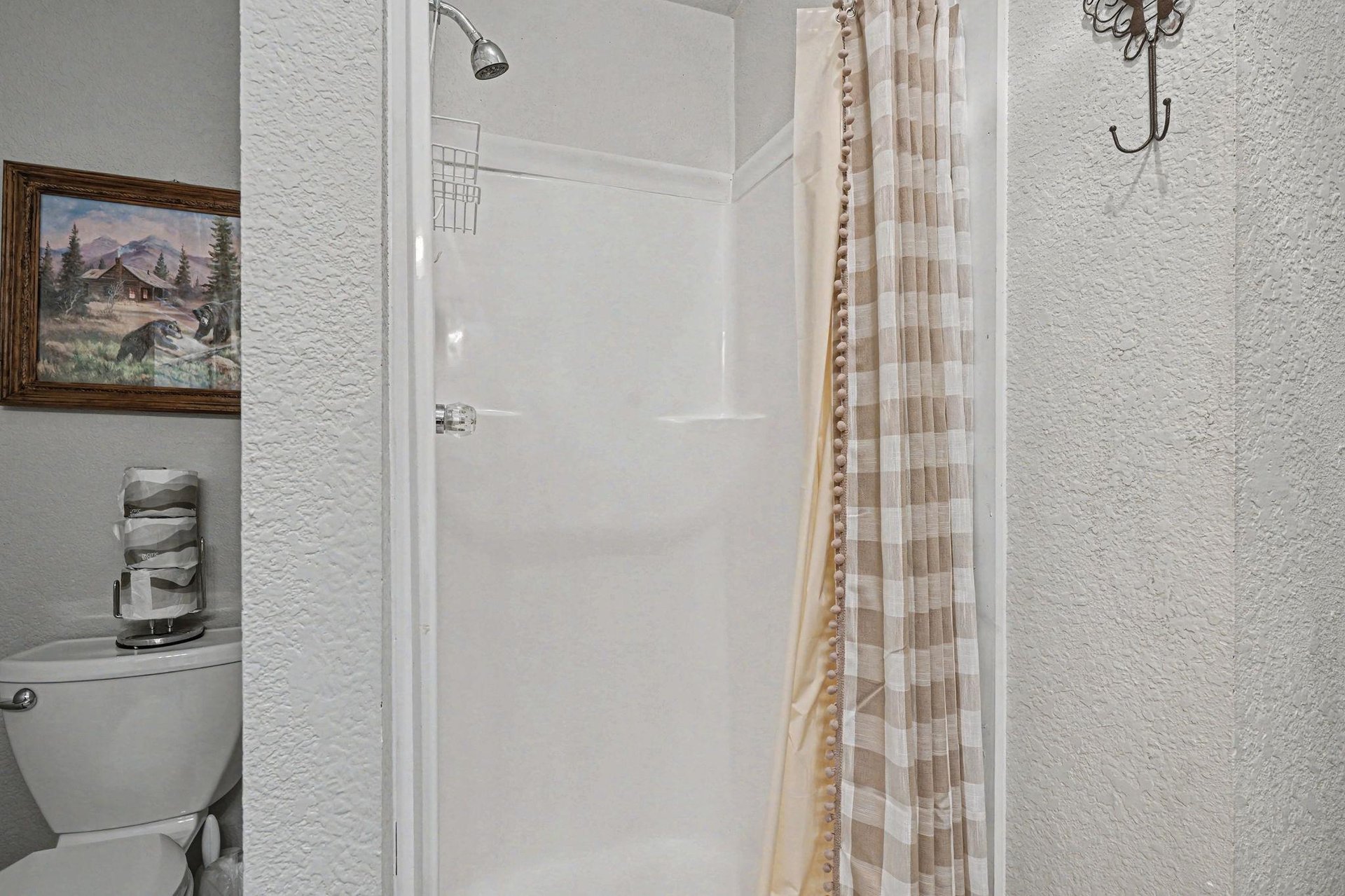Step into your private bathroom retreat with a spacious shower, modern fixtures, and charming cabin artwork creating a cozy mountain atmosphere.