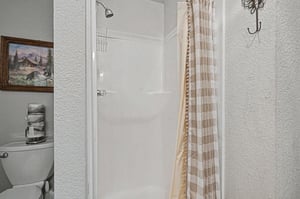 Step into your private bathroom retreat with a spacious shower, modern fixtures, and charming cabin artwork creating a cozy mountain atmosphere.