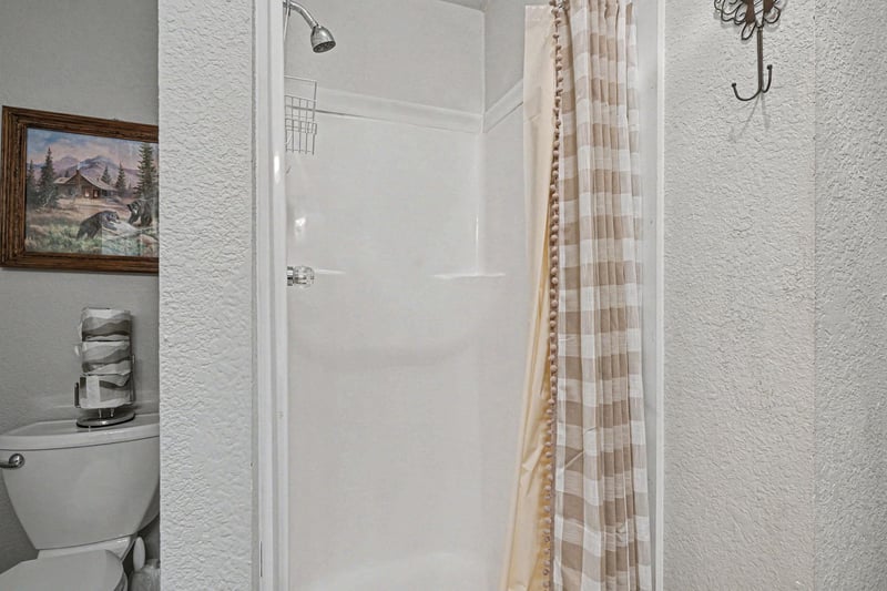 Step into your private bathroom retreat with a spacious shower, modern fixtures, and charming cabin artwork creating a cozy mountain atmosphere.