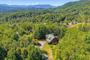 Aerial view showcasing the propertys secluded mountain setting, surrounded by dense forest and offering dramatic longrange views of the Smoky Mountain ridges.