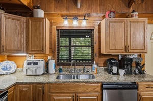 Step into a warm, cabinstyle kitchen with natural wood accents and modern conveniences—your coffee station awaits while you enjoy peaceful views of the surrounding greenery.